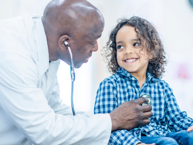 a doctor checking the patient's heart during their well-child check