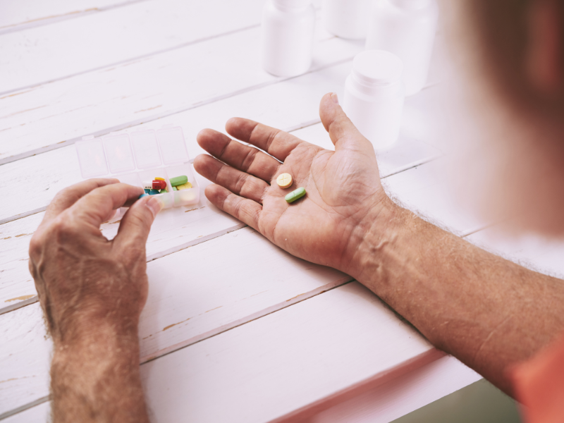 a person's hands outstretched on a table with a few medications in their hand