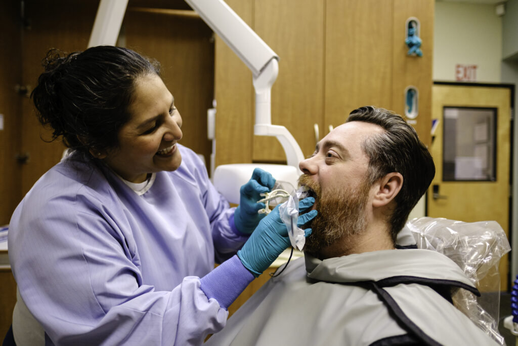 a dental hygienist working on a patient's teeth in a community health center