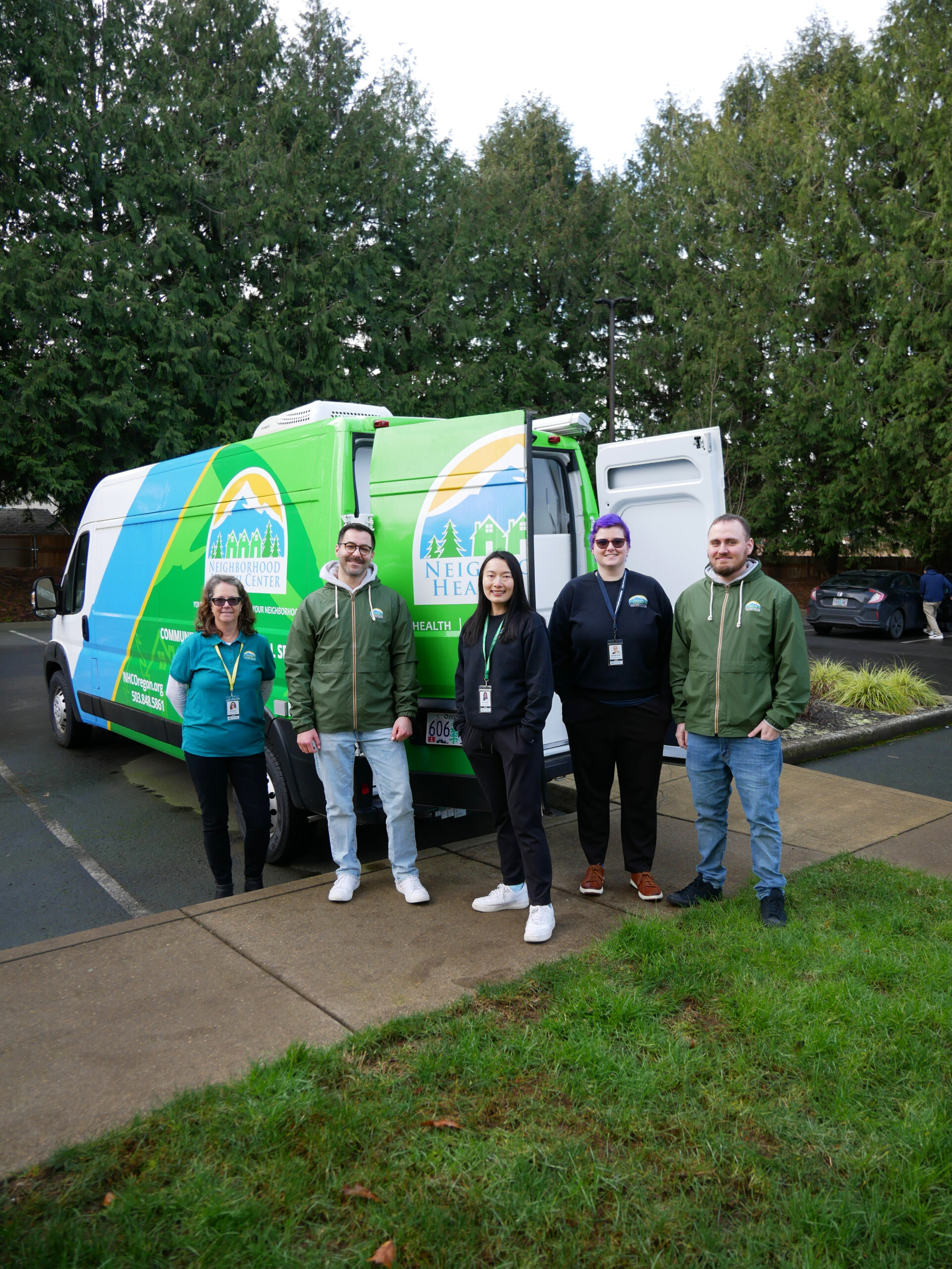 a group of people standing in front of an NHC van