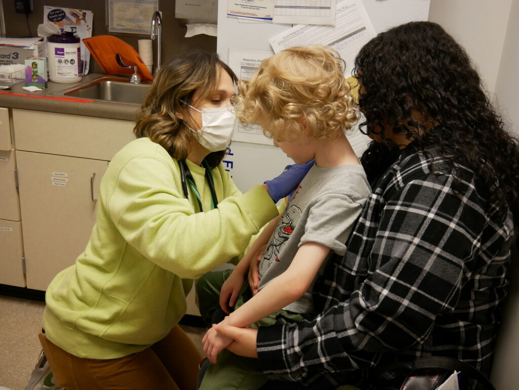 a provider administering a vaccine while the patient sits on their mother's lap