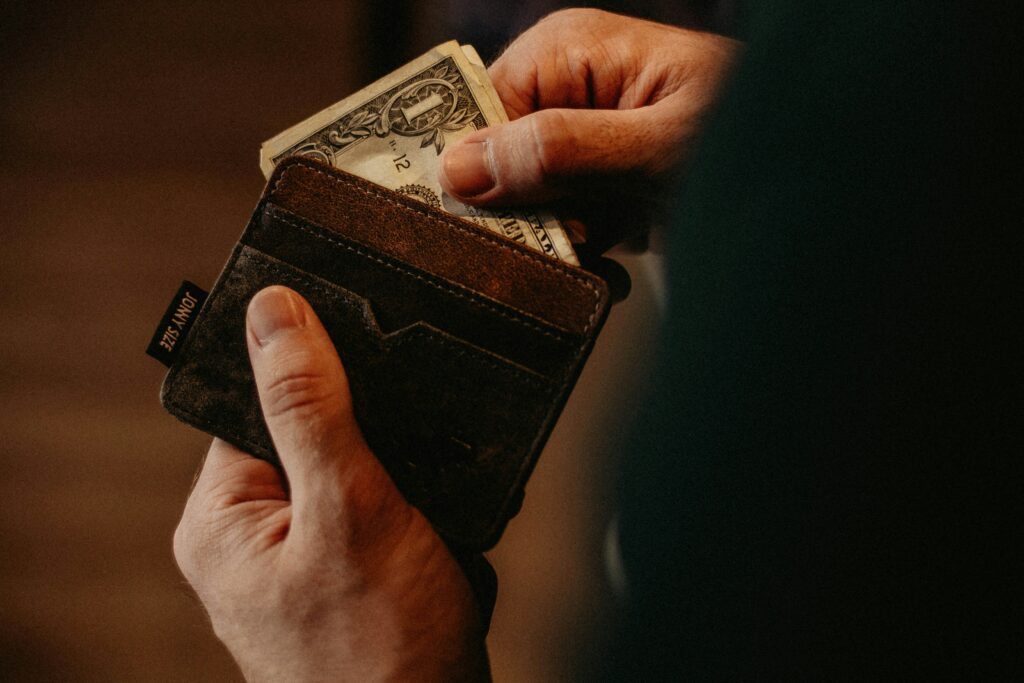 allef-vinicius-fJTqyZMOh18-unsplash a hand pulling out a dollar bill from a leather wallet to support community health centers