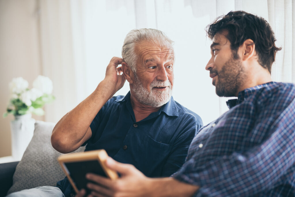 An adult hipster son and senior father at home, talking. adult chatting with a senior