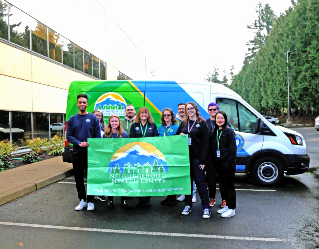 a group of nhc staff members standing in front of a van holding up an nhc sign