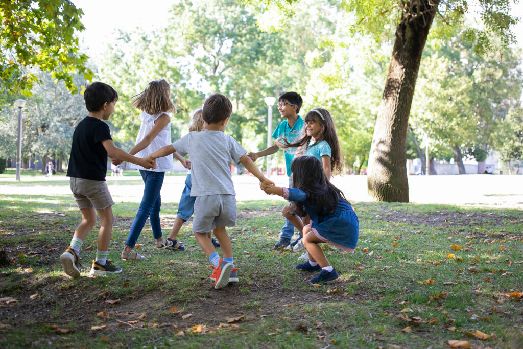 several kids holding hands in a circle in a park