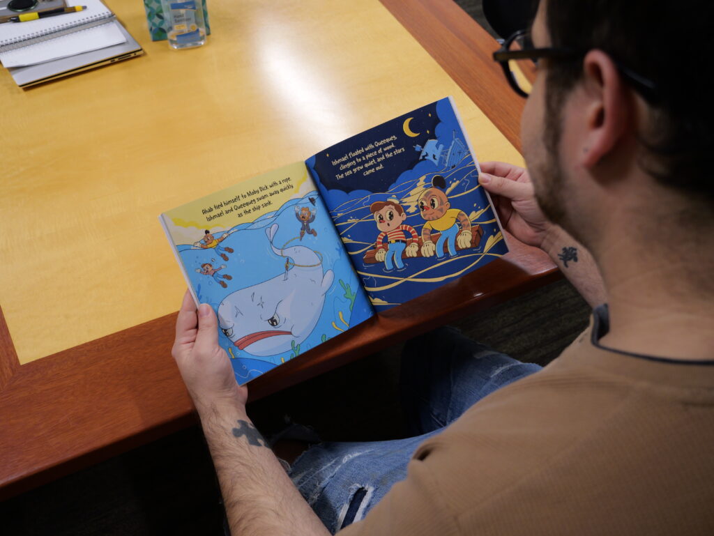 NHC IT Coordinator flips through his self-published book