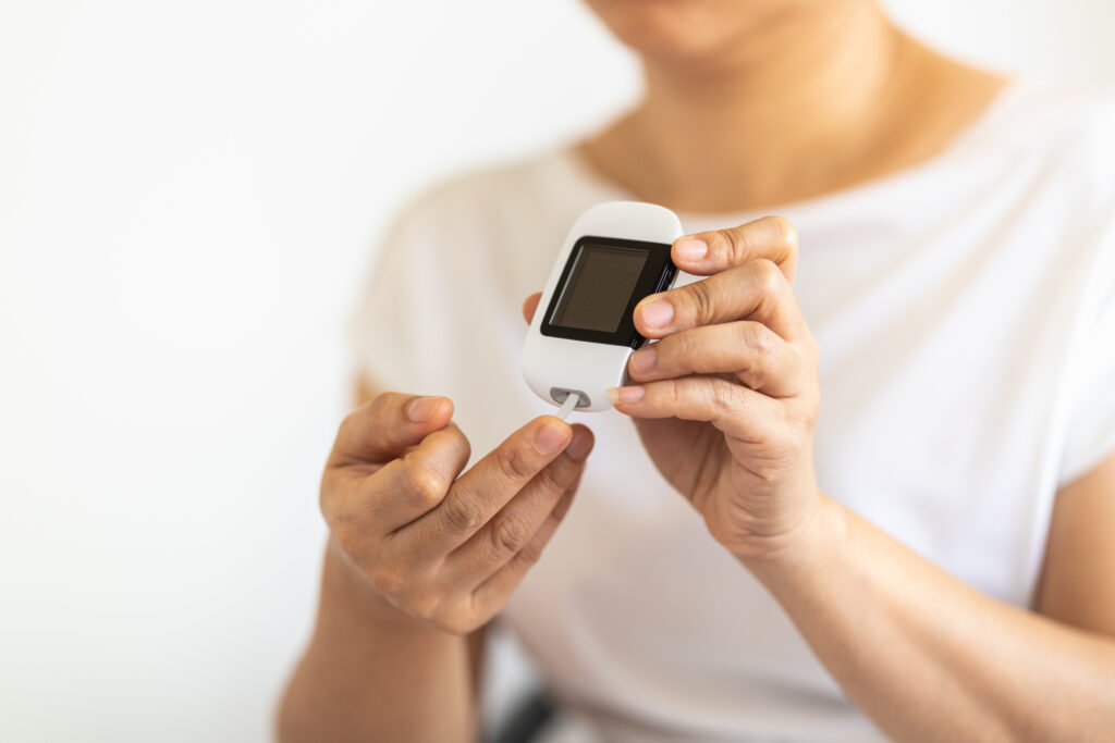 a woman using a glucose meter on her finger to check blood sugar level