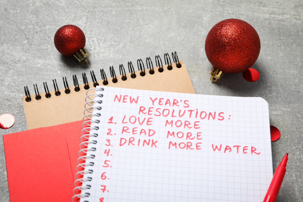 a notebook with a list of new year resolutions such as loving more, reading more, and drinking more water