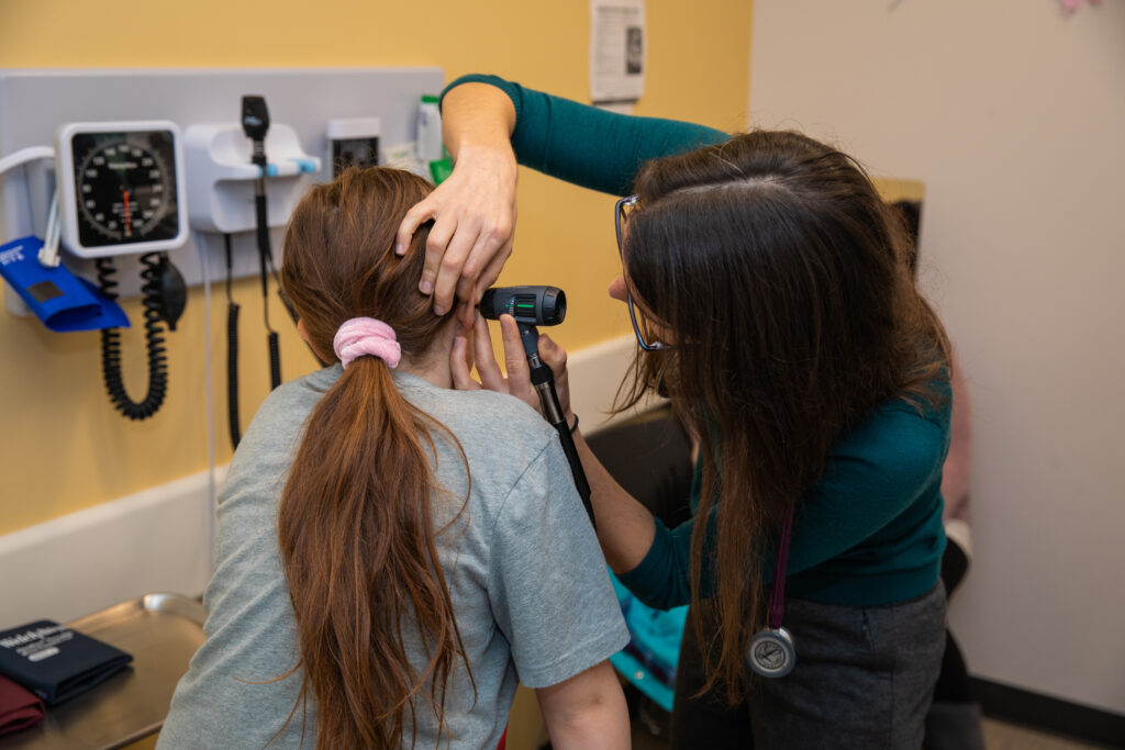a primary care provider checking the ears of their patient during a wellness exam