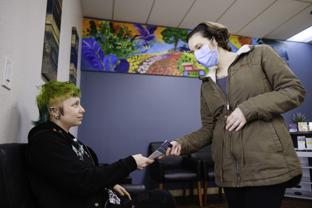 a primary care provider hands a patient a brochure while they're sitting in the lobby