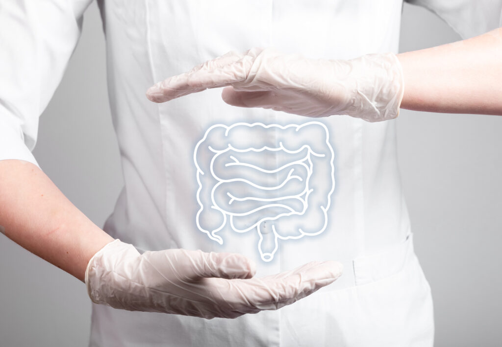a doctor with their hands hovering over their stomach with a graphic between the hands illustrating the colon