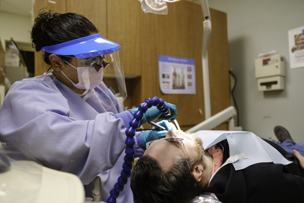 a dental hygienist performing a cleaning on a patient during a regular dental checkup