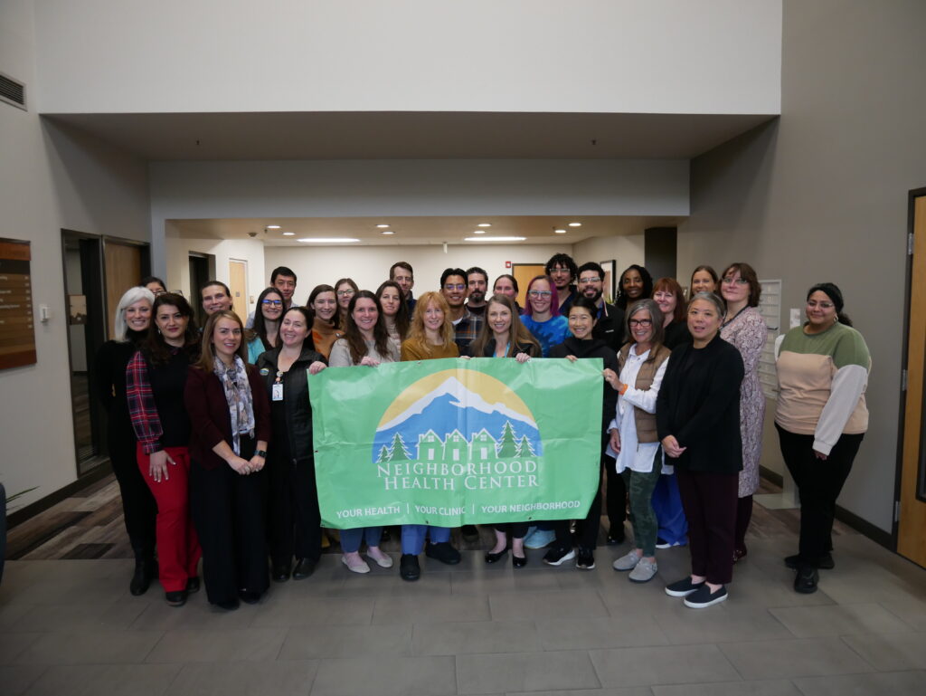 a large, diverse group of healthcare providers holding up an NHC banner