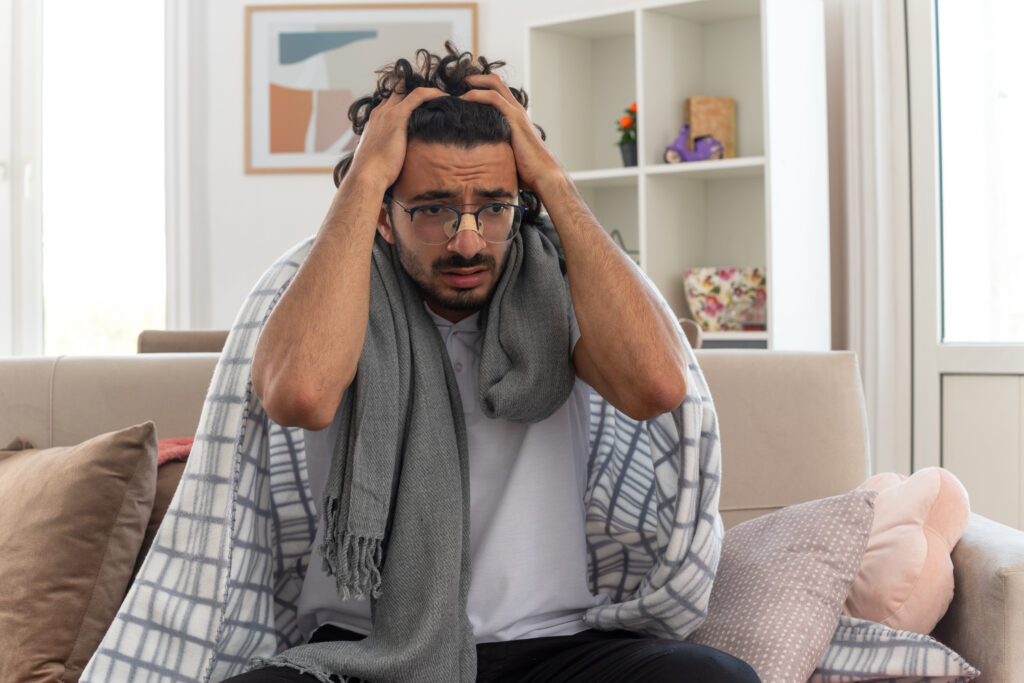 a man sitting on a couch running his hands through his hair