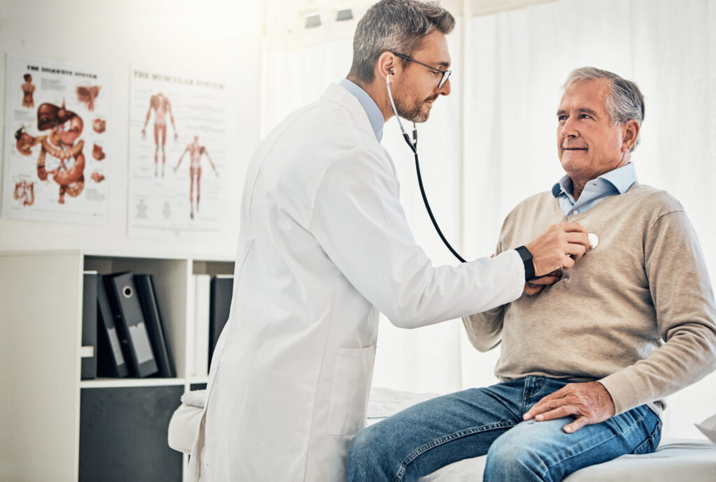a doctor using a stethoscope to check the heart of their senior patient during a wellness exam