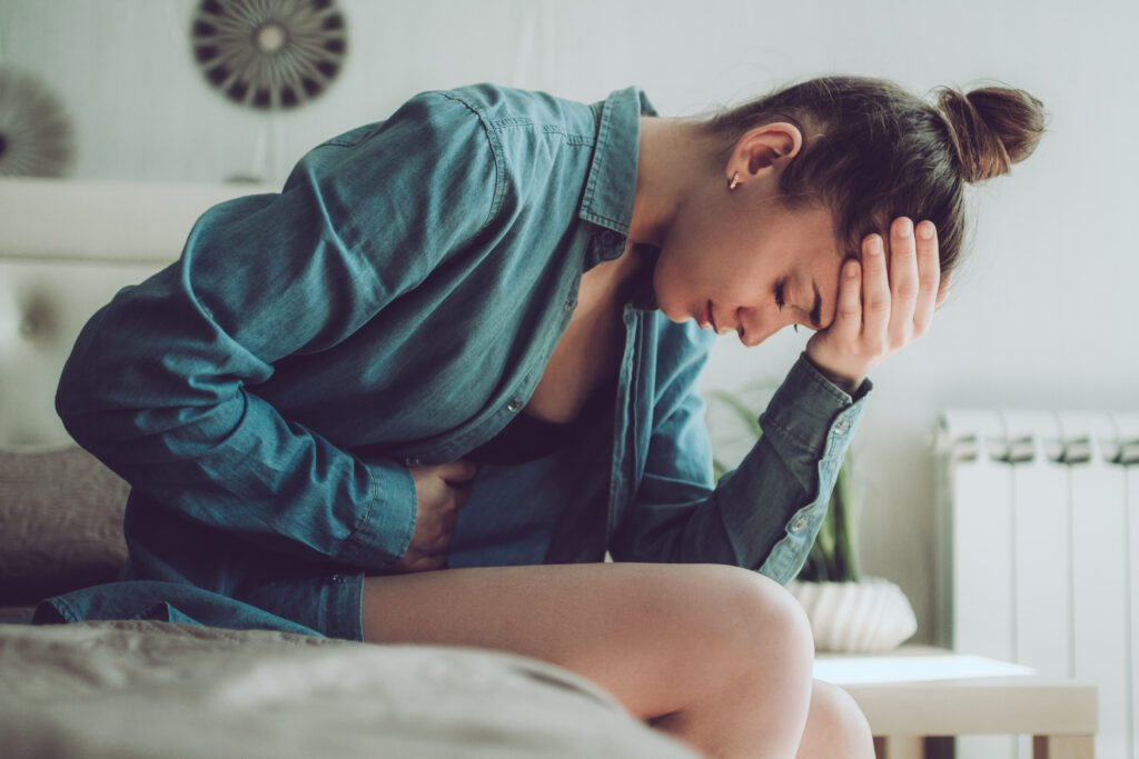 a woman sitting on a bed hunched over