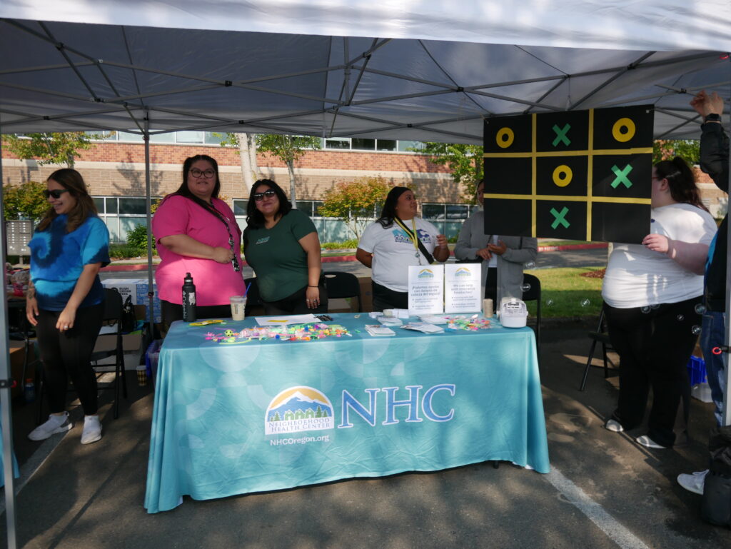 three NHC employees standing behind a table at the health fair