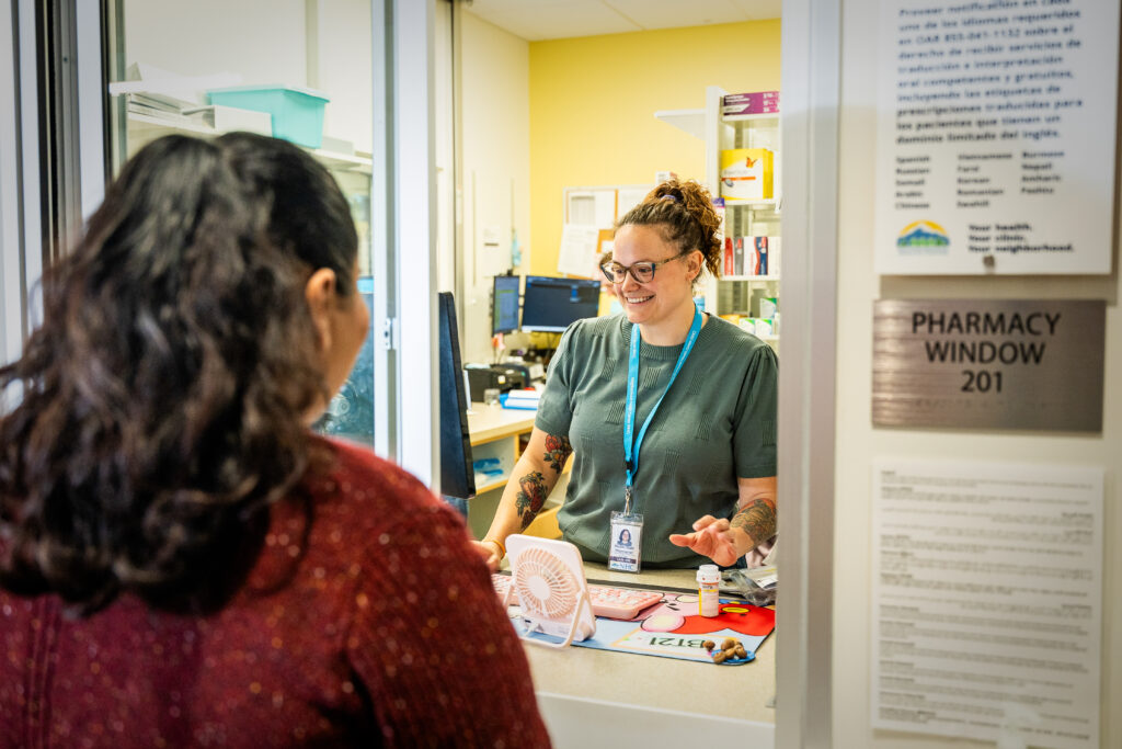 a patient talking with a pharmacist while picking up their medication