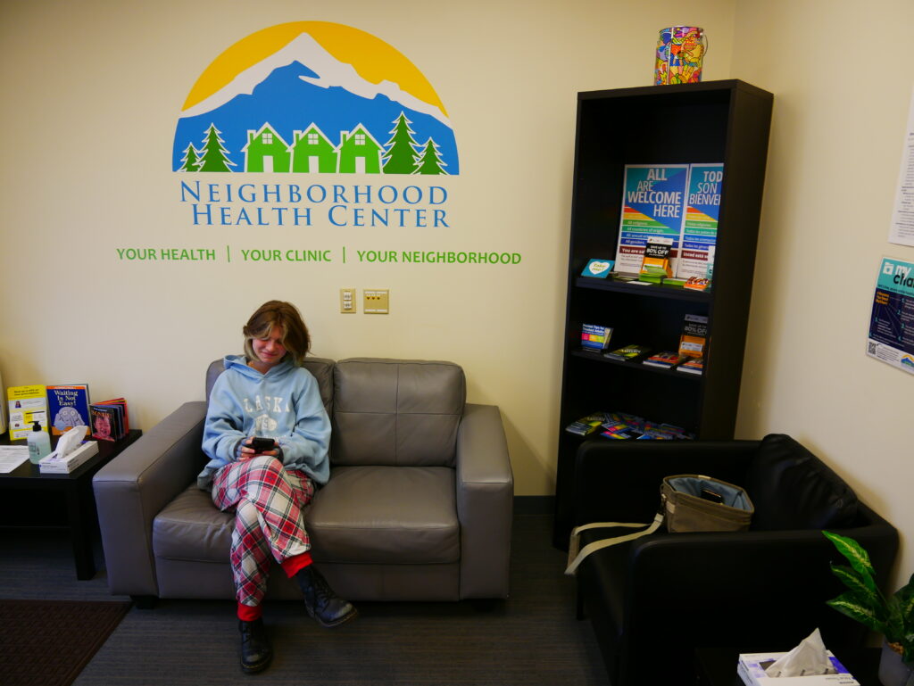 a student sitting in the lobby of a school-based health center