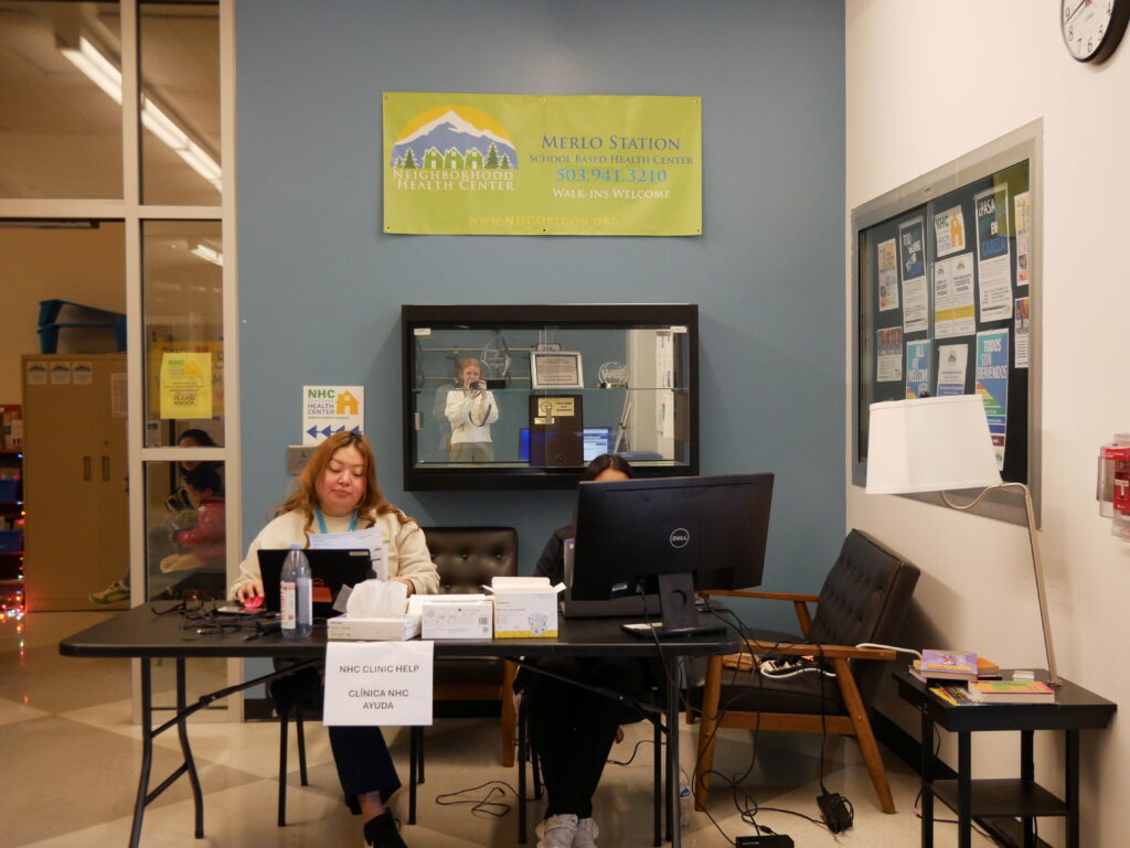 staff sitting at a desk in front of the Merlo school-based health center
