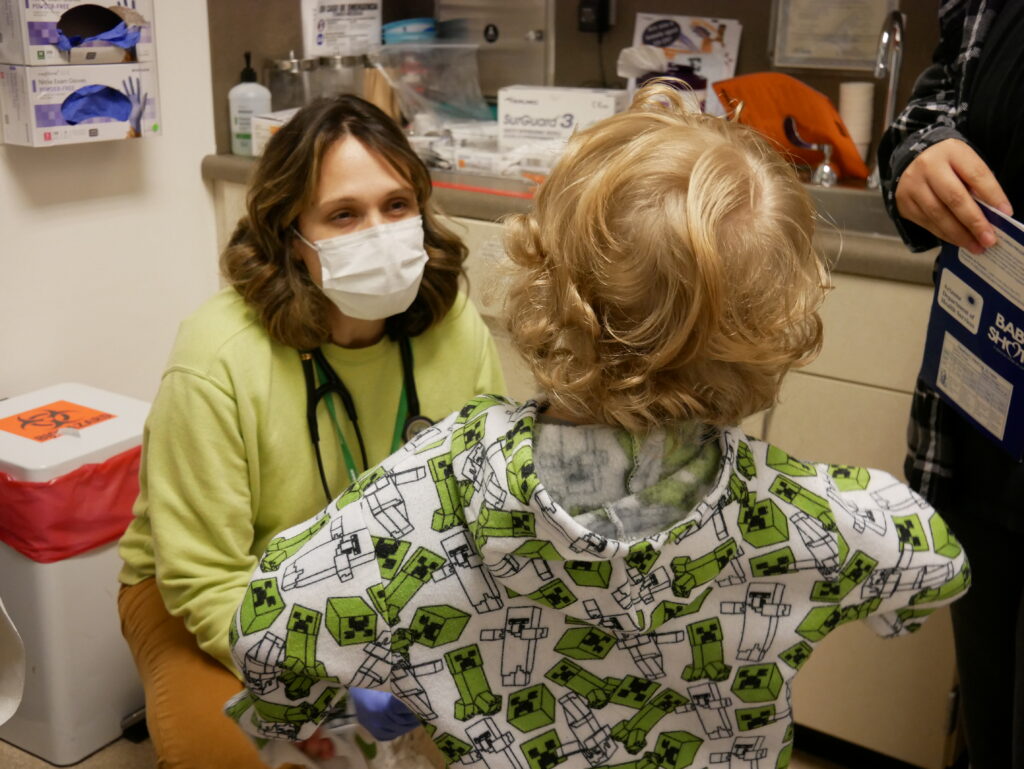 a healthcare provider talking to a young child at his wellness checkup