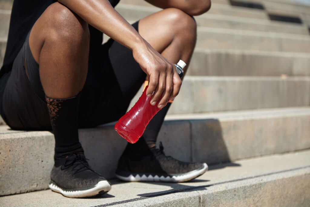 a close up of a man sitting on steps holding a sports drink