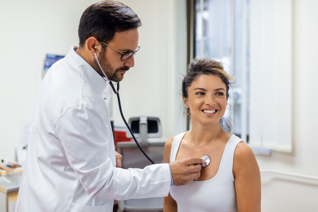 a doctor listening to a patient's heartbeat with a stethoscope at her first appointment