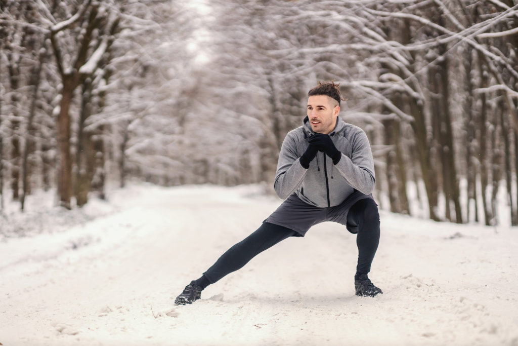 man stretching outdoors in a forest during the winter